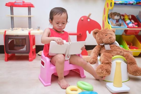 Bebé sentada en una silla con un libro, aplicando estrategias de lectura